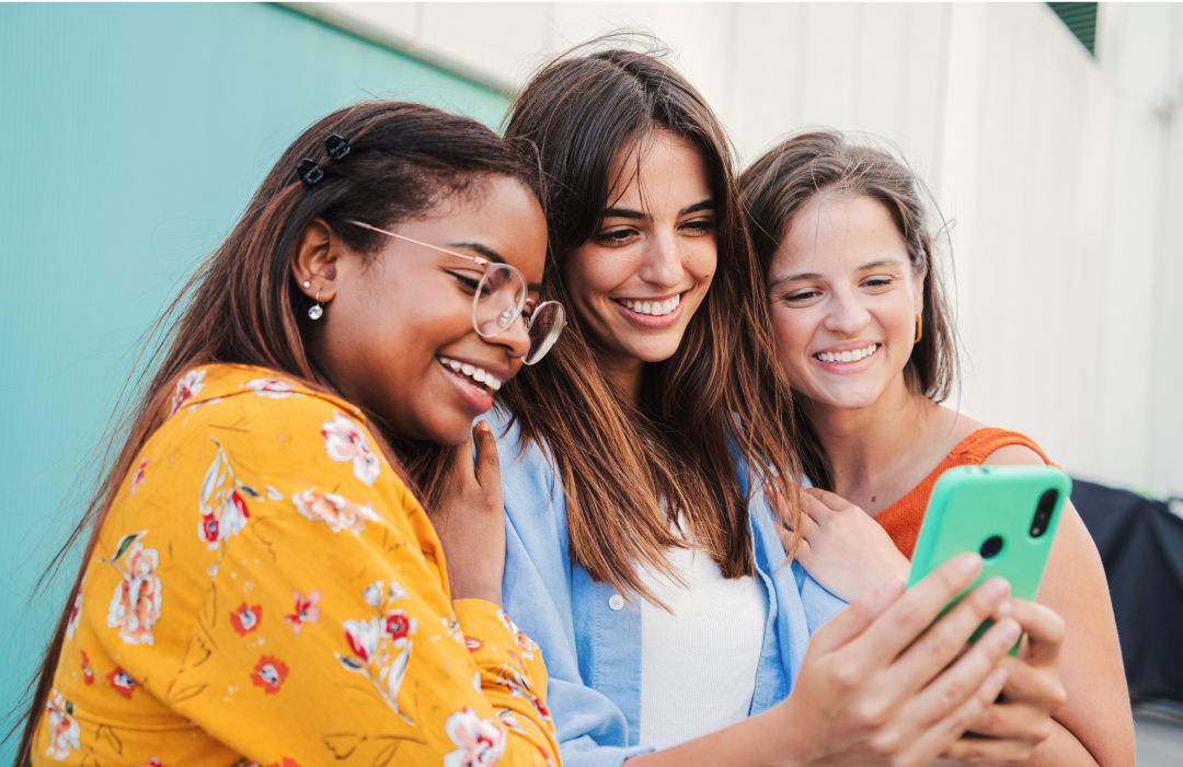 women smiling and looking at a phone together